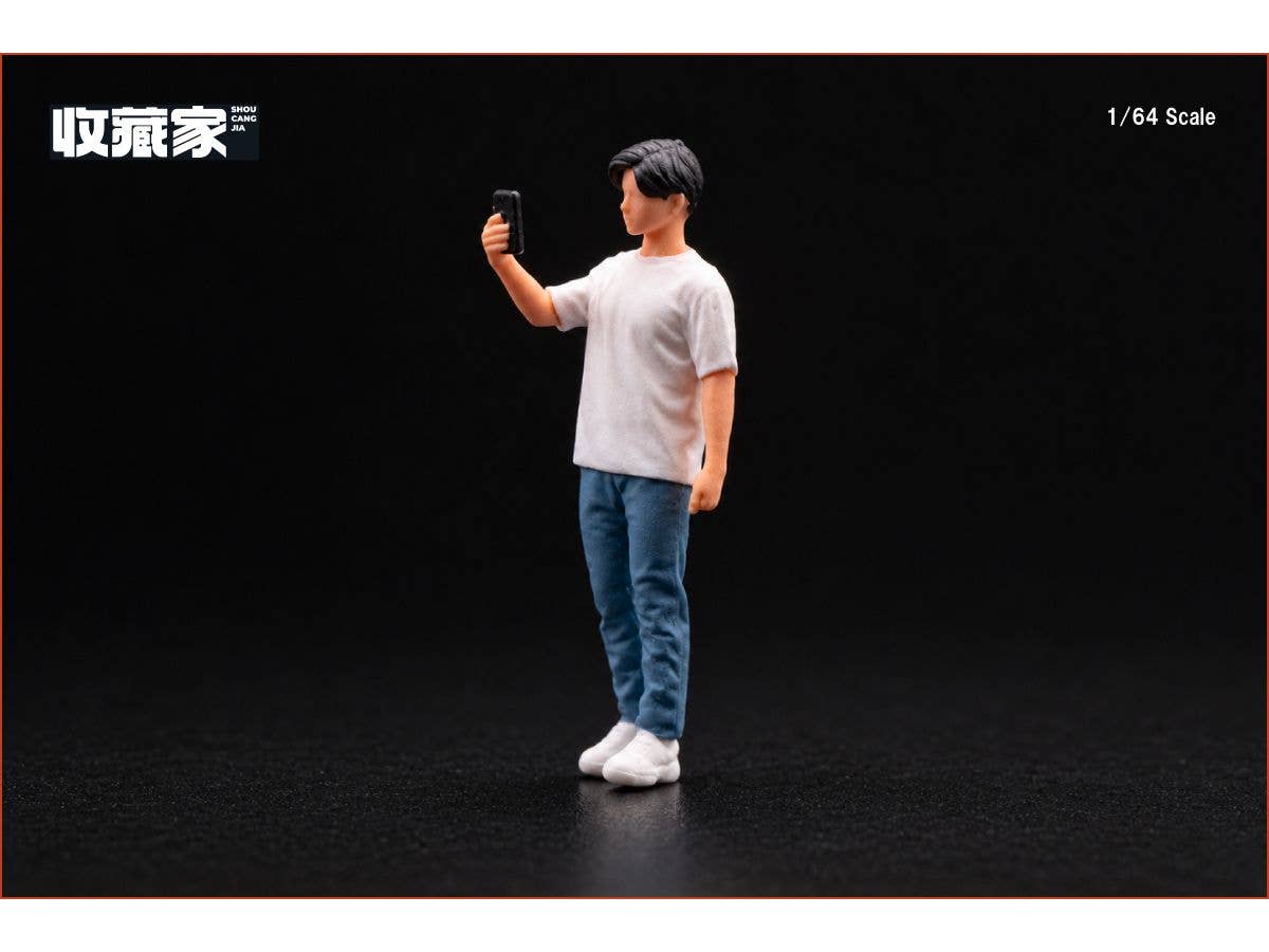 A man (wearing white clothes) is holding up his smartphone and taking a picture.